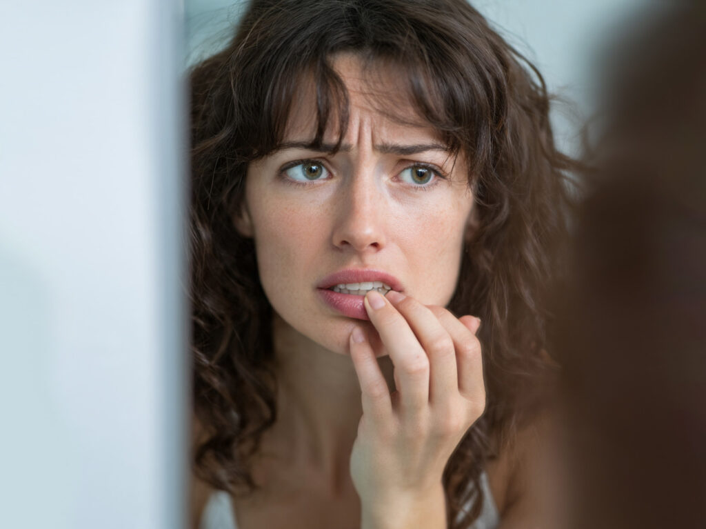 Primer plano mujer con unos dientes con desgaste dental, una de las consecuencias de morderse las uñas.